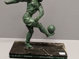 statue of a man kicking a soccer ball on a marble base