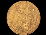 une image représentant une assiette en or sur laquelle figurent une femme et un chien