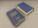 two blue books sitting on top of a table next to each other
