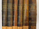six vieux livres sont alignés sur une surface blanche