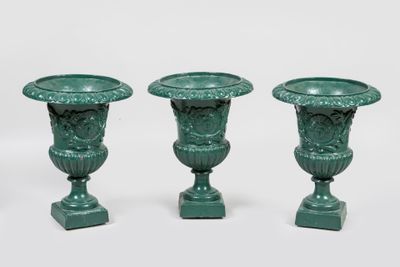 trois vases verts posés les uns à côté des autres sur une surface blanche