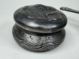 a silver box with a handle on a white table