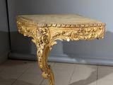 une table dorée avec un plateau en marbre, posée sur un sol carrelé