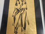 two black and gold framed pictures of two women standing next to each other