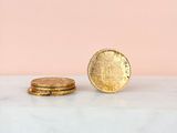a gold coin sitting on top of a marble counter next to a stack of coins