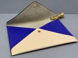 porte-monnaie bleu et blanc en forme de triangle, orné d'un pompon, sur fond gris
