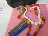 un sac à main, un collier de perles et une paire de ciseaux posés sur une table