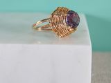 a close up of a gold ring with a purple stone in it