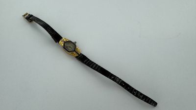 l'image d'une montre noire et or sur une surface blanche