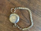 a close up of a watch on a chain on a wooden table