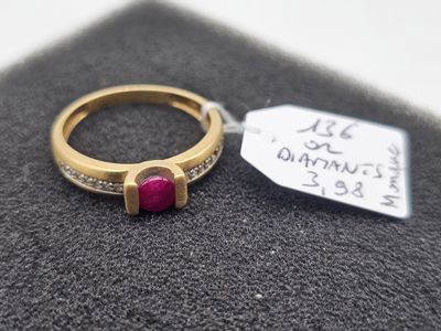 a gold ring with a red stone and a tag