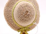 un chapeau de paille orné d'un ruban vert, posé sur un support en bois