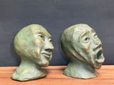 pair of bronze heads of two men on a wooden table