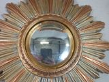 a gold starburst mirror on a white wall