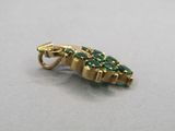 a close up of a gold pendant with green stones on it