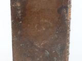 an old book sitting on top of a white table next to a white wall