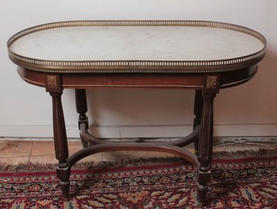an oval table with a marble top on a rug in front of a white wall