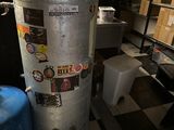a water heater in the corner of a room next to a blue stool
