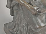 statue of a woman sitting on a chair reading a book