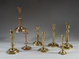 several brass candlesticks are lined up on a white surface