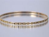 gros plan d'un bracelet en or sur une surface blanche