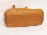 tan leather handbag with gold studded handles on a white background