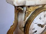 a white clock with gold decorations on top of it