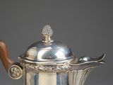 an antique silver tea pot with a wooden handle on a table