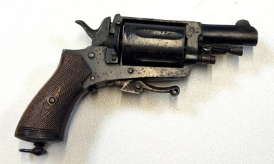 un petit revolver posé sur une surface blanche