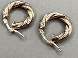 pair of silver hoop earrings with twisted ends on a gray surface