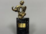 une statue représentant un homme tenant une batte de baseball, posée sur un socle en marbre noir