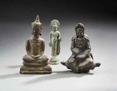 trois figurines en bronze représentant des bouddhas assis sur une surface blanche
