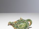an image of a green and gold teapot sitting on a white surface