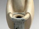 a statue of a man sitting on a pedestal holding a pot
