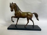 statue d'un cheval au galop sur un socle noir, sur fond blanc