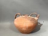 un grand vase marron posé sur une surface grise