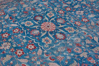 a blue rug with a red and white flower design on it