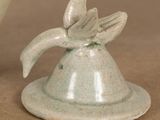 a small ceramic bell with a flower on top of it