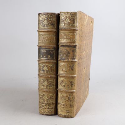 two old books sitting on top of each other on a white surface