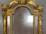 a mirror with a gold frame on the wall