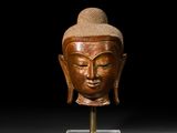 une image représentant une tête de Bouddha en bois posée sur un socle
