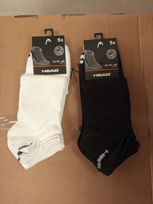 deux paires de chaussettes de tennis noires et blanches posées sur une boîte en carton