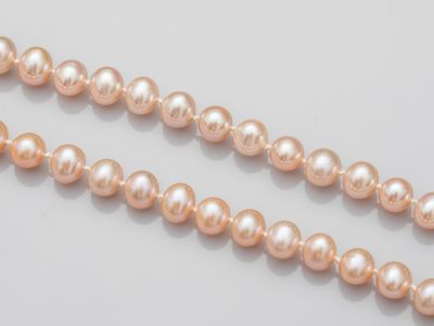 a close up of a strand of pink pearls on a white surface