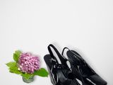 black high heeled shoes next to a vase with a flower