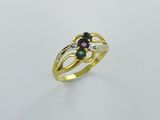 un gros plan d'une bague en or sertie de deux pierres vertes et roses