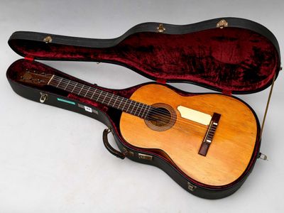 une guitare dans un étui, posée sur une surface blanche
