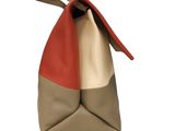 beige and red handbag on a white background with a red handle