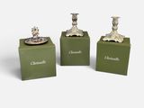 three silver candlesticks on green boxes on a white background