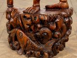 a wooden sculpture of a person sitting on top of a pile of fish