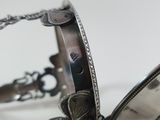 a close up of a silver bracelet on a white surface